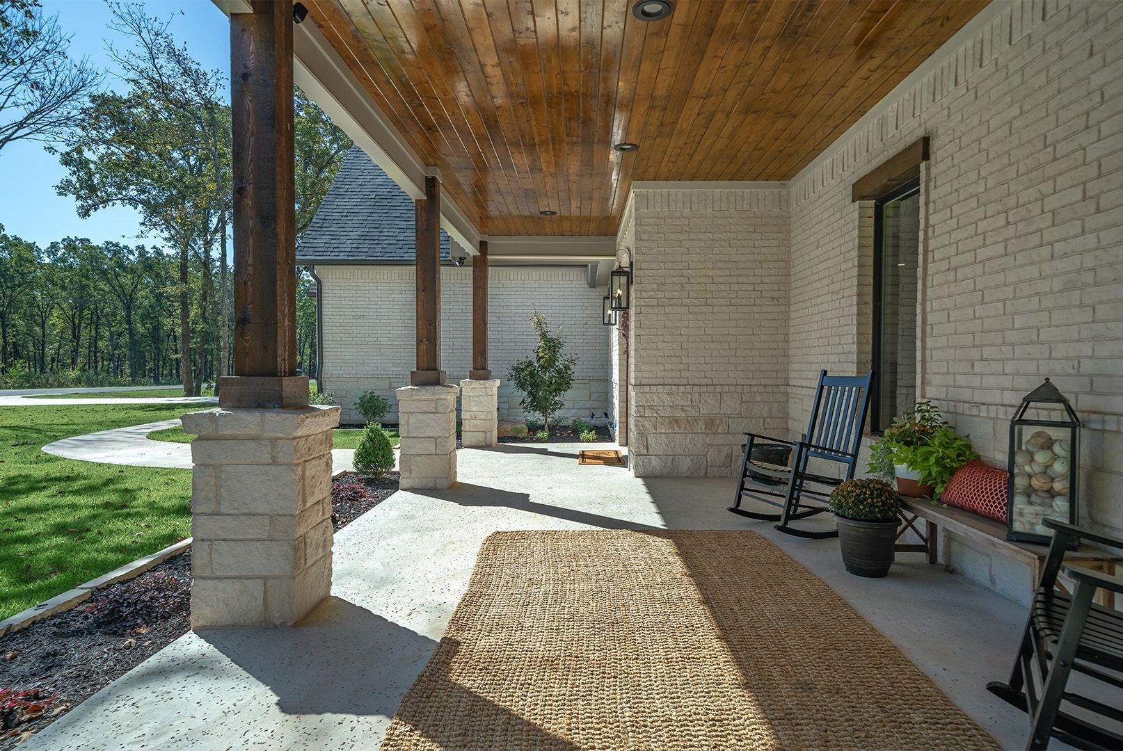 A porch with rocking chairs and a wooden ceiling