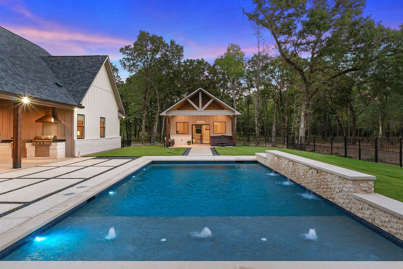 A large swimming pool is in the backyard of a house.