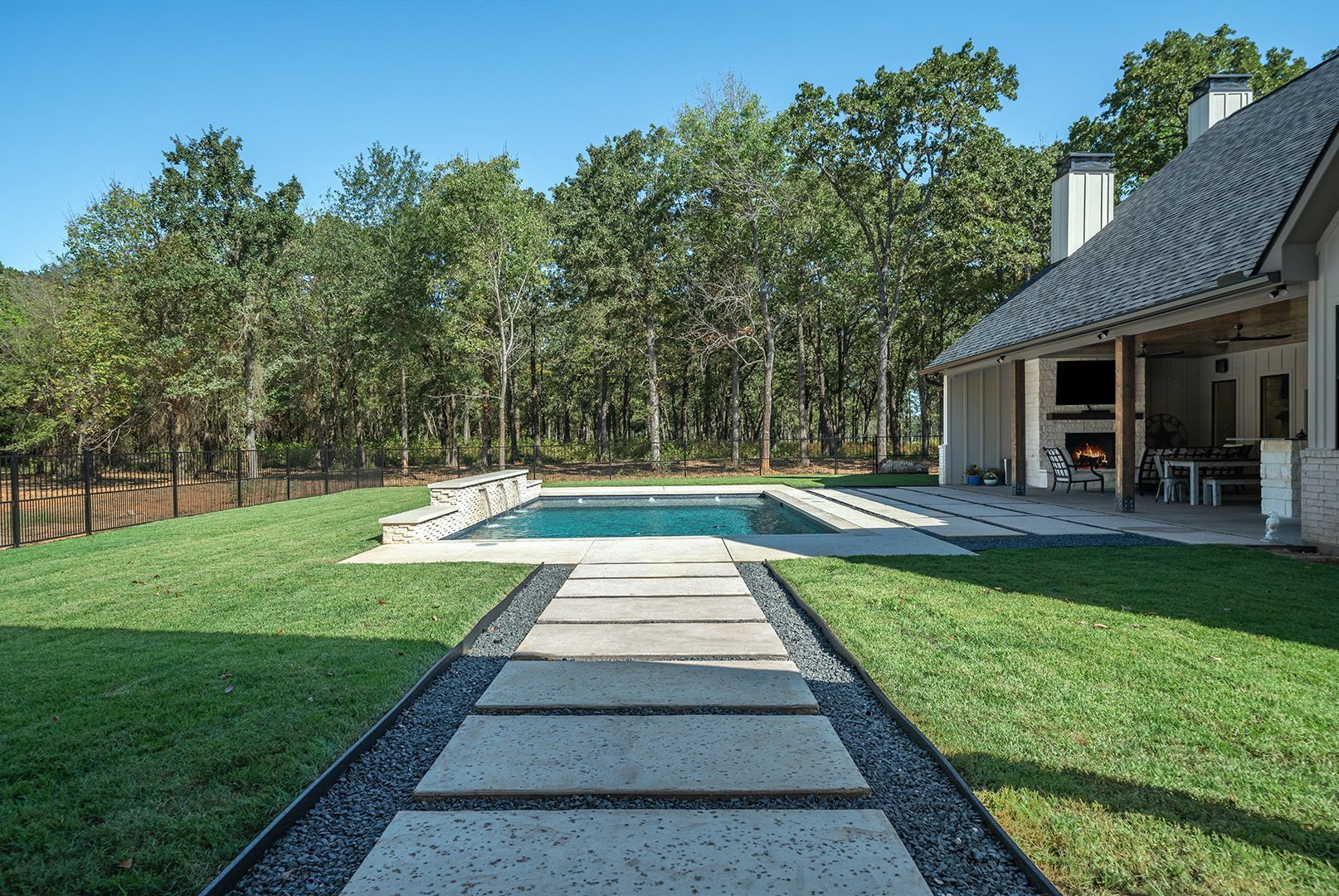 There is a large swimming pool in the backyard of a house.