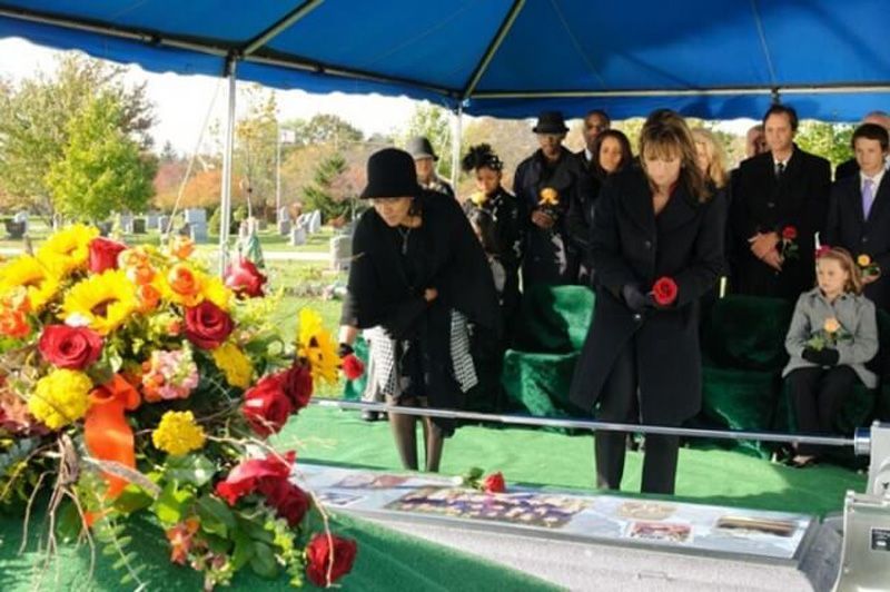a group of people standing around a coffin at a funeral