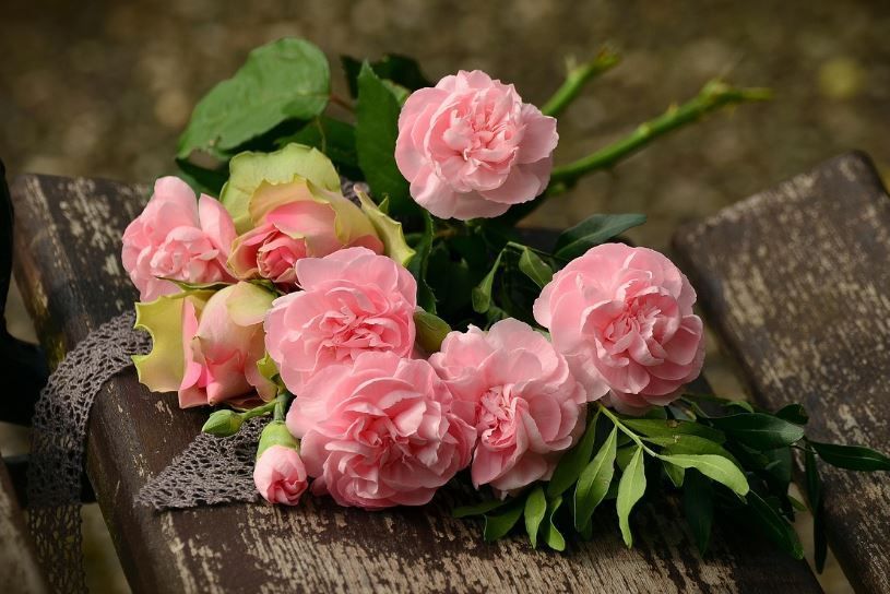 Pink roses and carnations arranged for Indianapolis, IN funeral services on a rustic bench