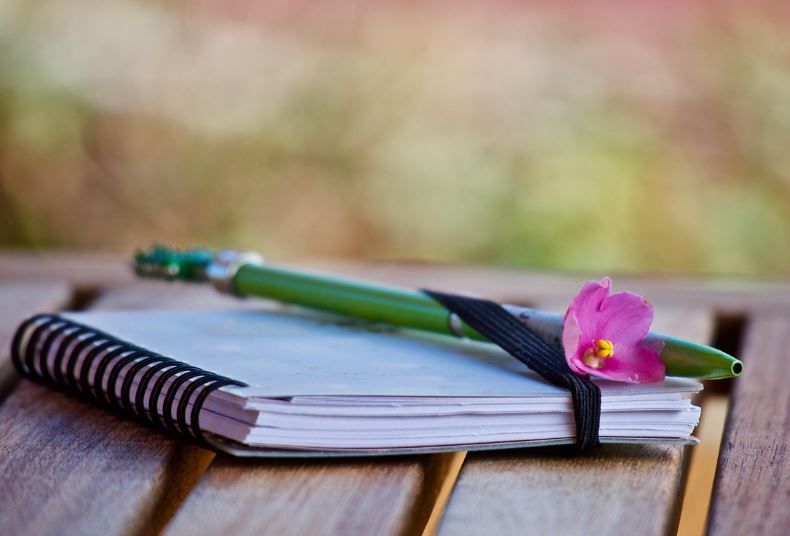 Planner and green pen with pink flower on table, Carmel, IN funeral homes preplanning guidance