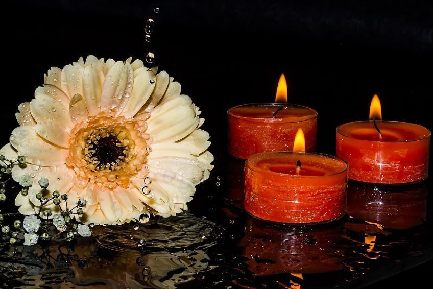 White flower beside lit red candles with reflections, Indianapolis, IN cremation services