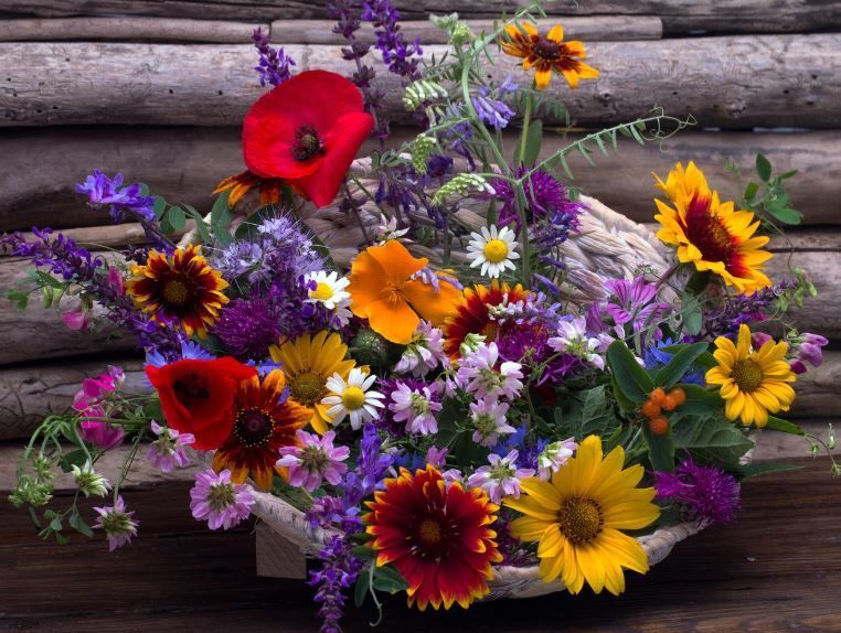 Bright meadow flowers arranged in basket against rustic wood, Indianapolis, IN cremations