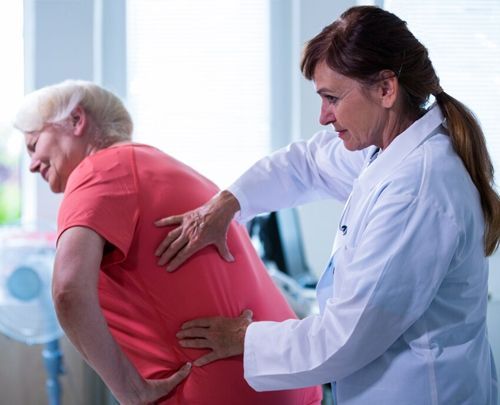 Doctor helping a patient with back pain in a bright clinic