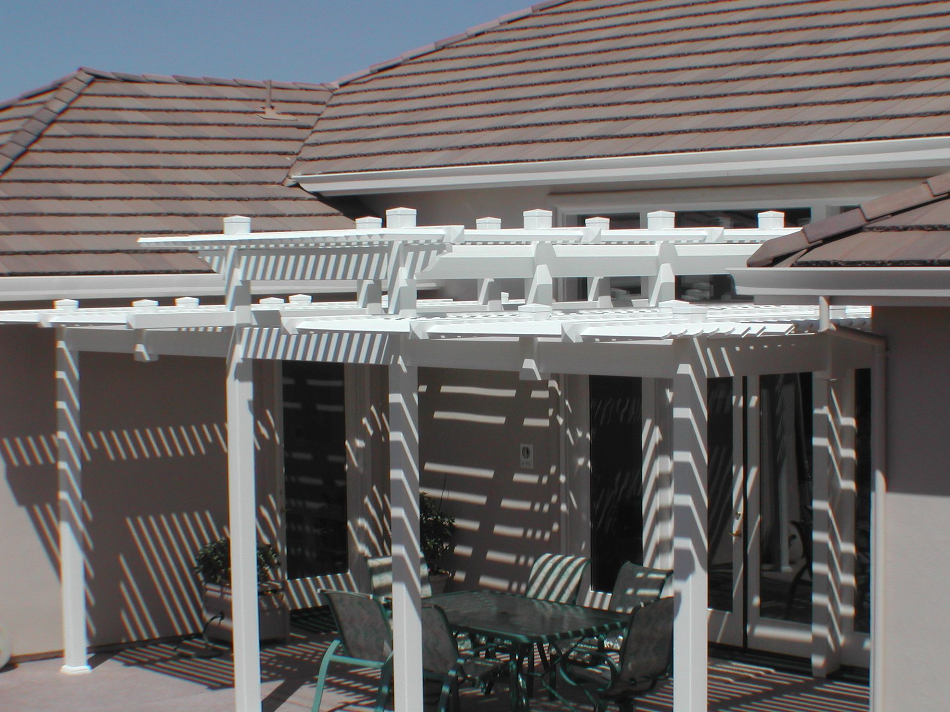 A white pergola with a table and chairs underneath it