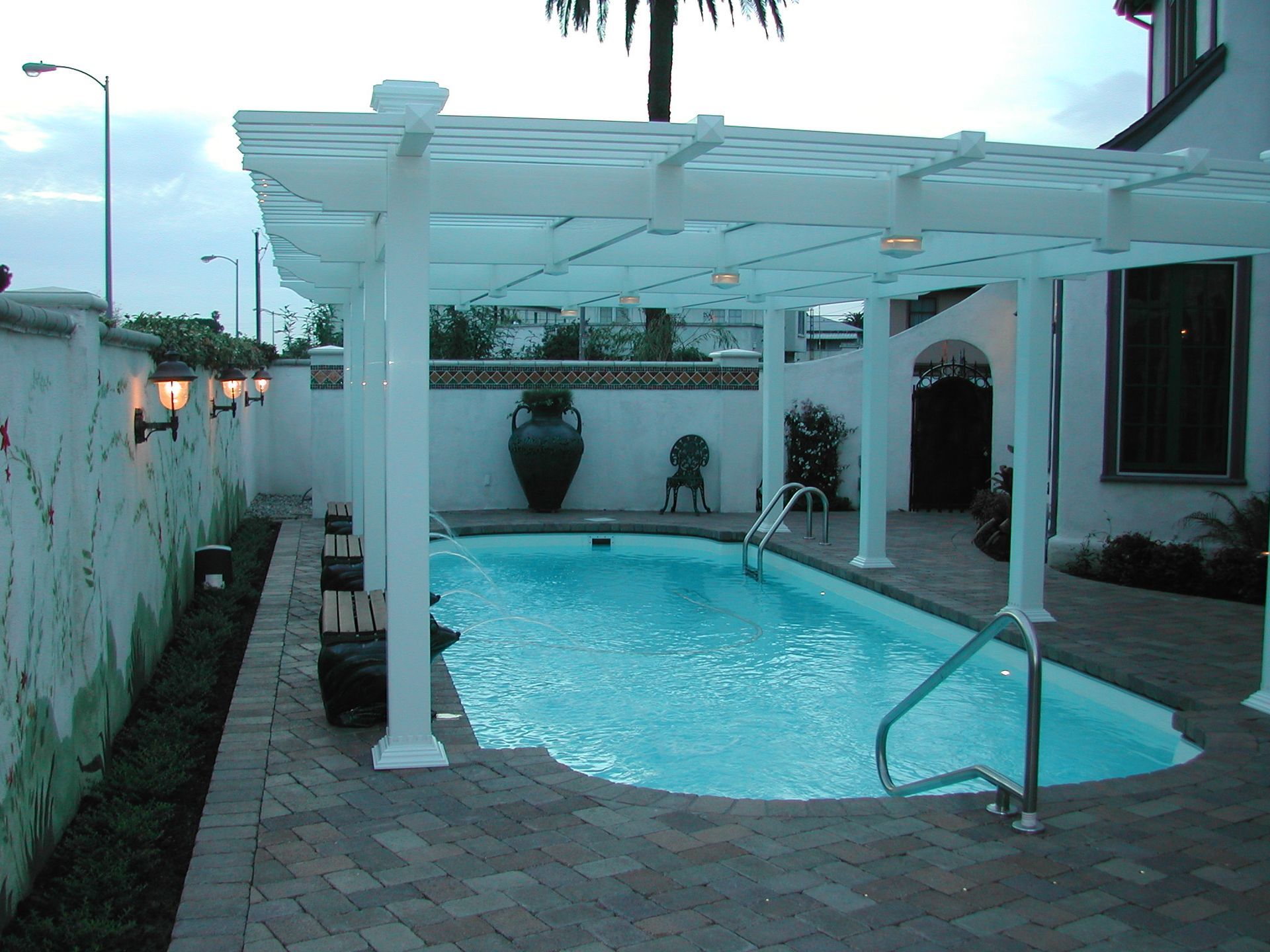 A large swimming pool with a white pergola over it