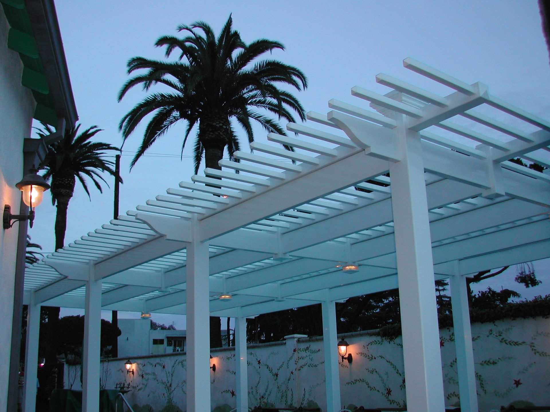A white pergola with palm trees in the background