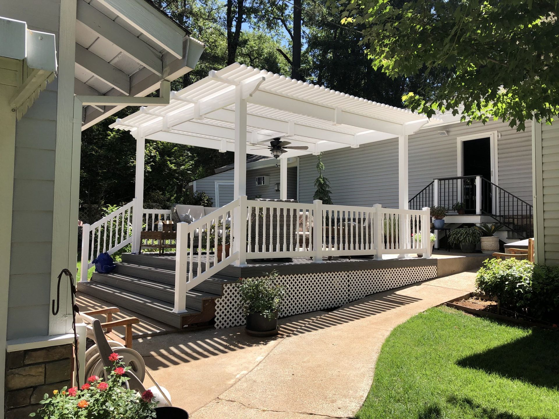 A white pergola is sitting on top of a patio next to a house.