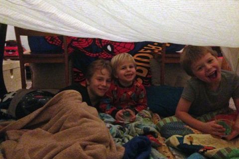 Blanket fort with three boys in it