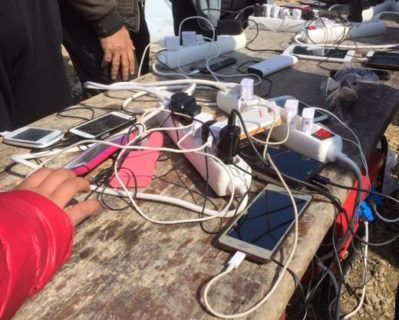 Cell phones at charging station in refugee camp. 