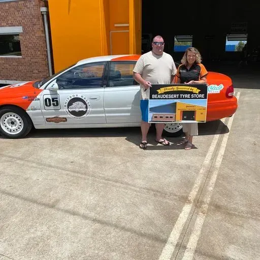A Man and Woman Holding a Signage — Beaudesert, QLD — Beaudesert Tyre Store