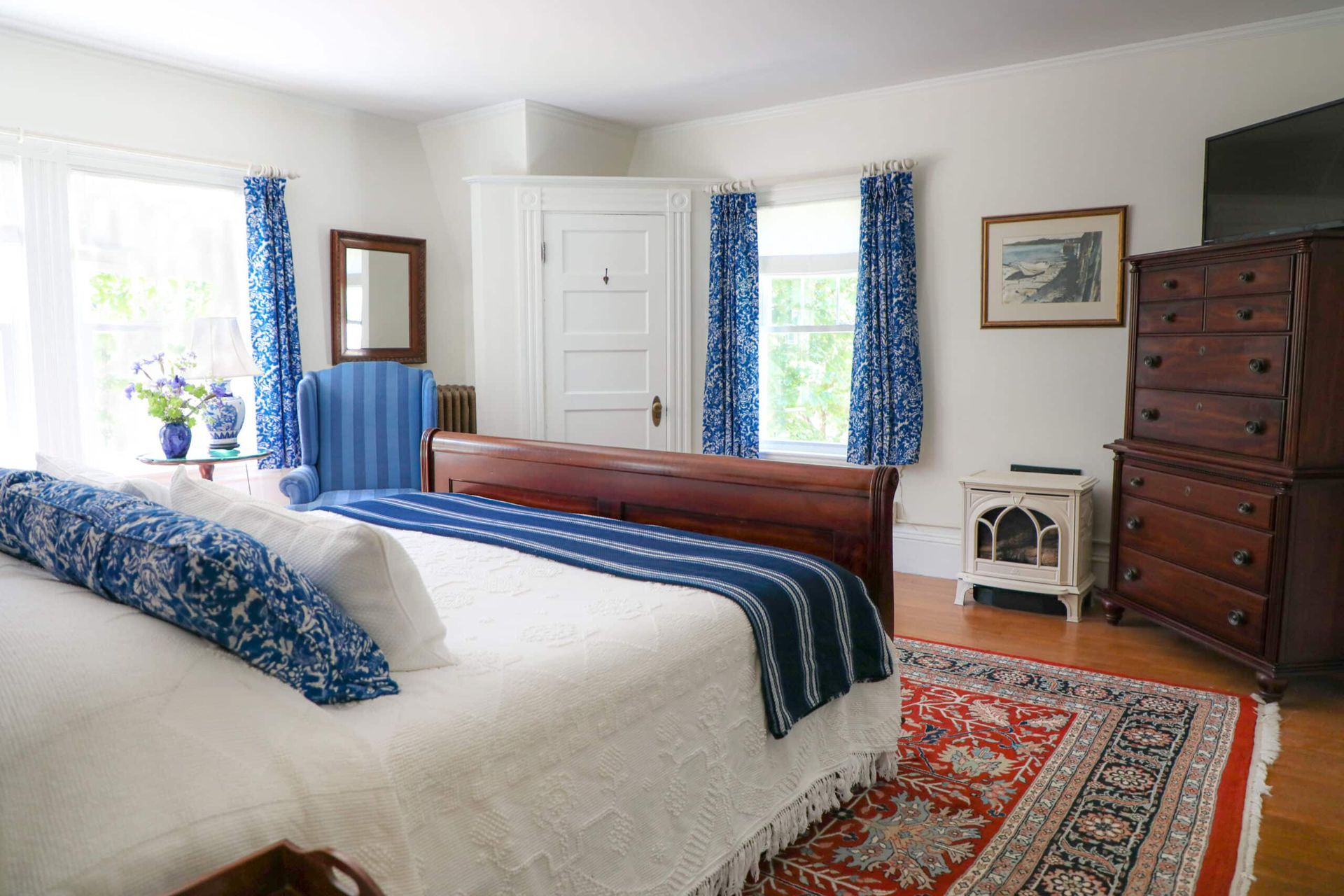 A bedroom with a large bed , dresser , and rug.