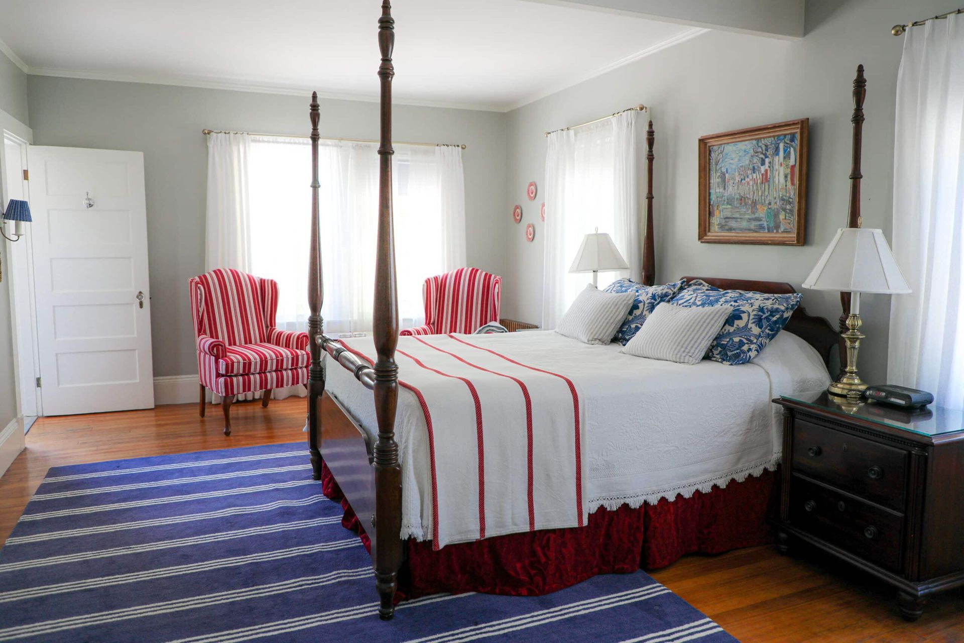 A bedroom with a four poster bed and two chairs