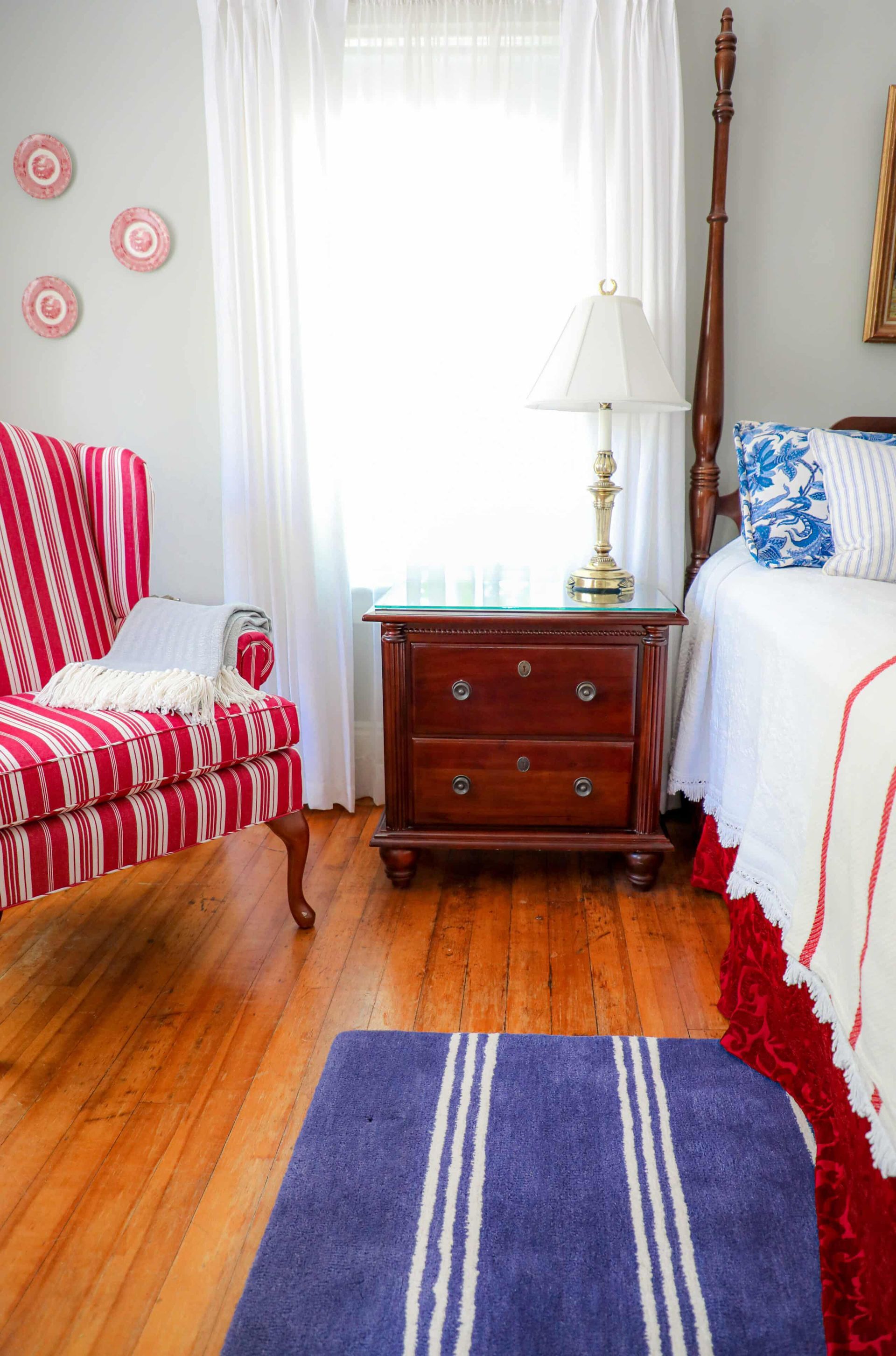 A bedroom with a bed , dresser , chair and rug.