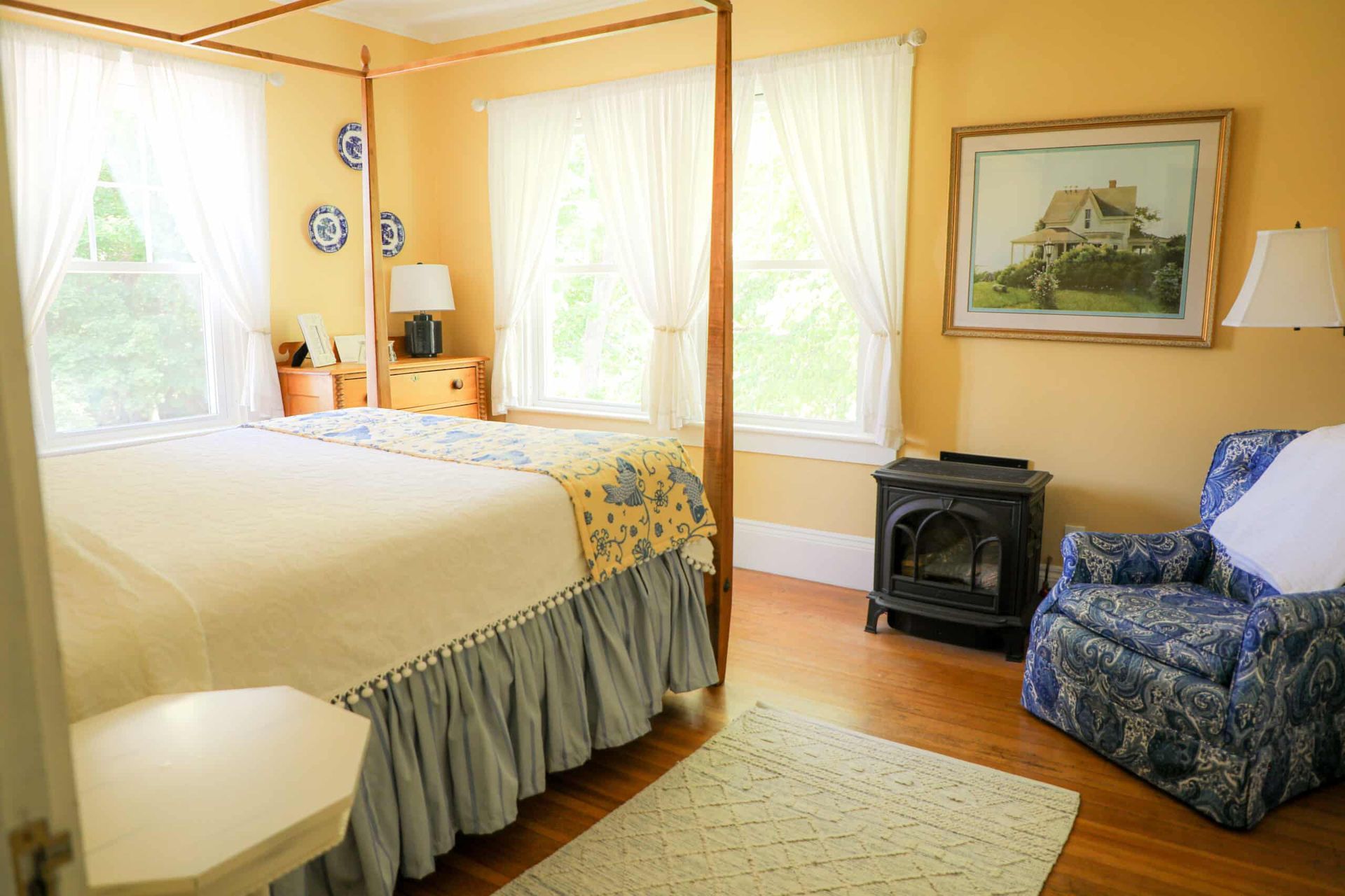 A bedroom with a four poster bed and a blue chair