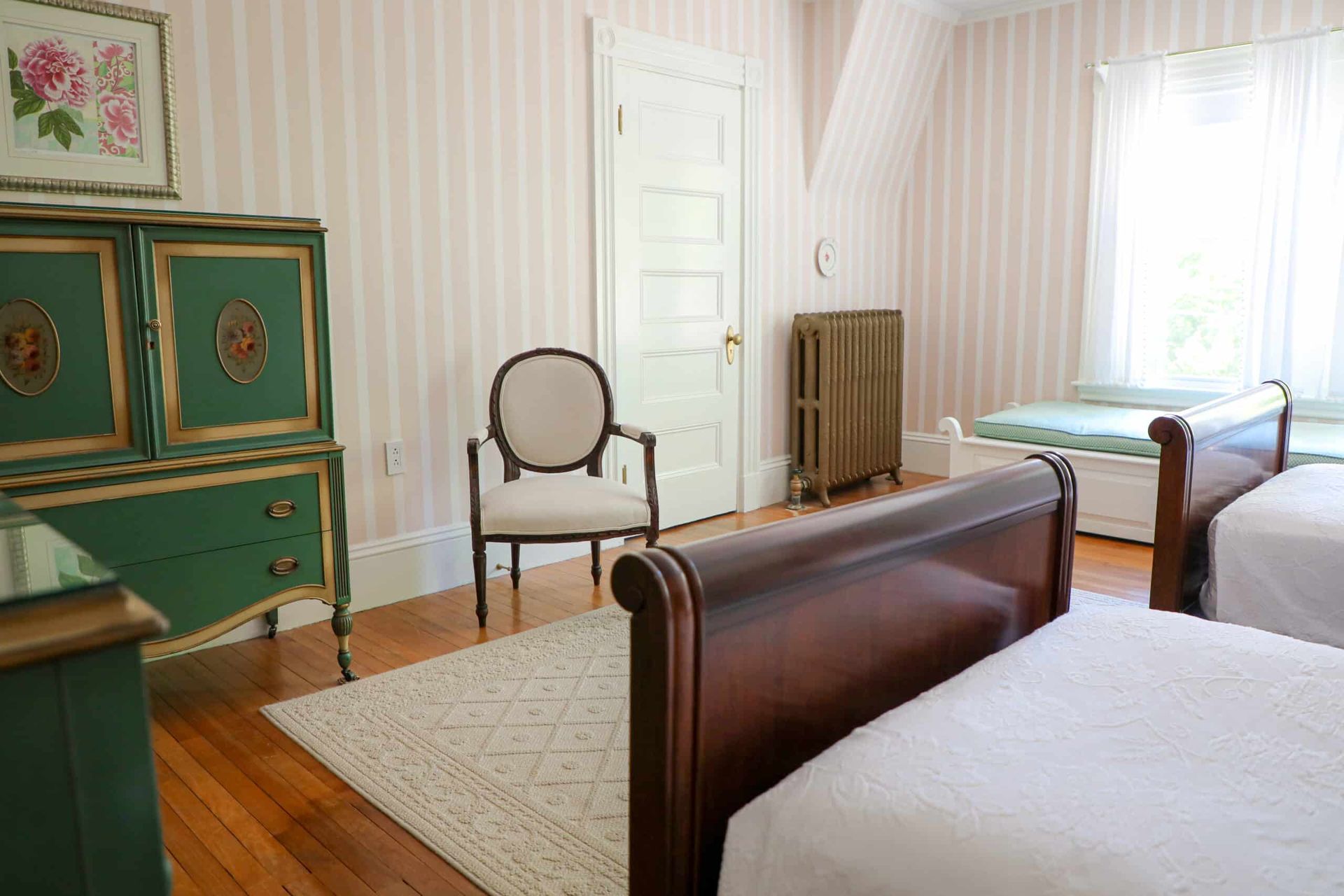 A bedroom with two beds , a chair and a dresser.