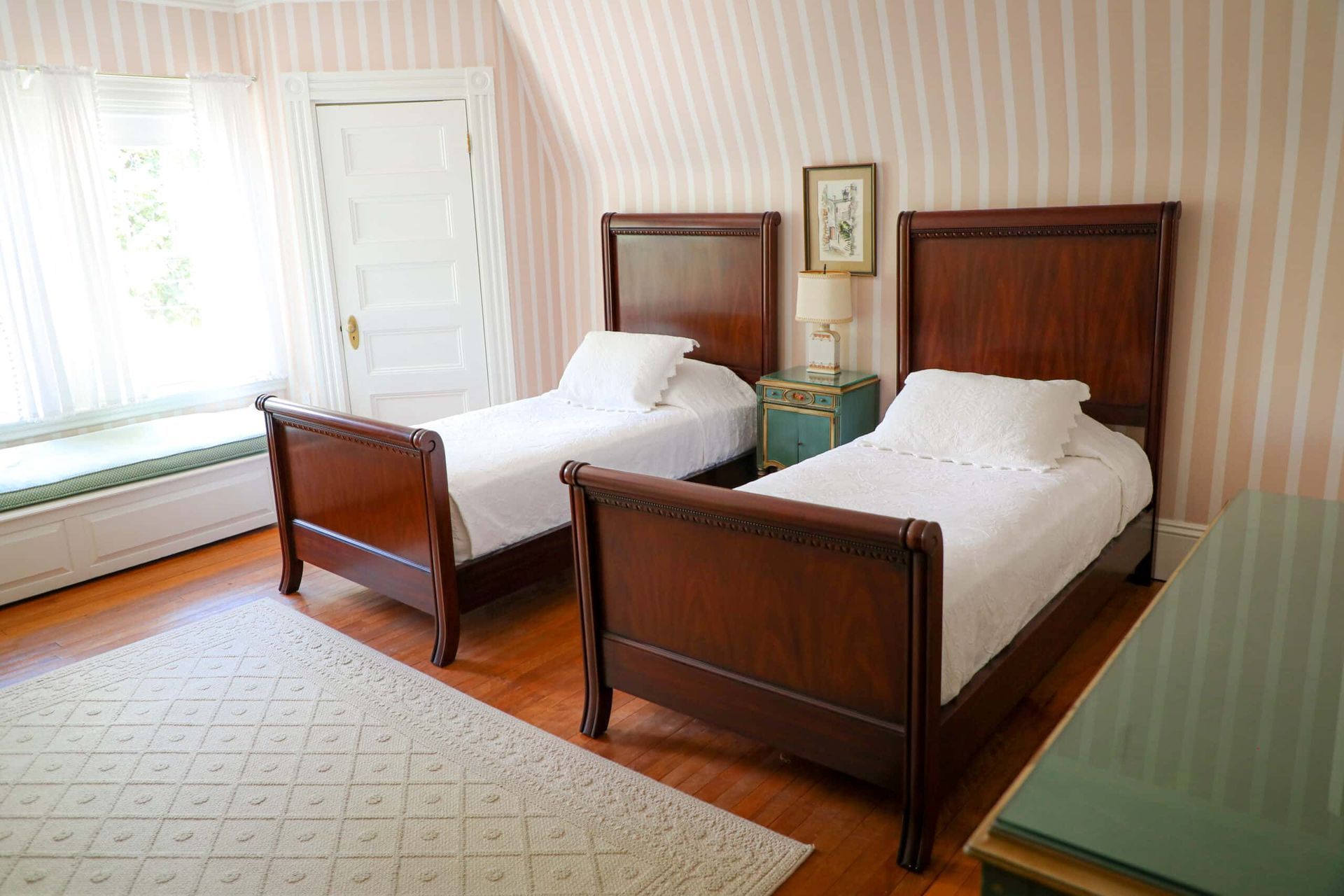 A bedroom with two twin beds and striped wallpaper.