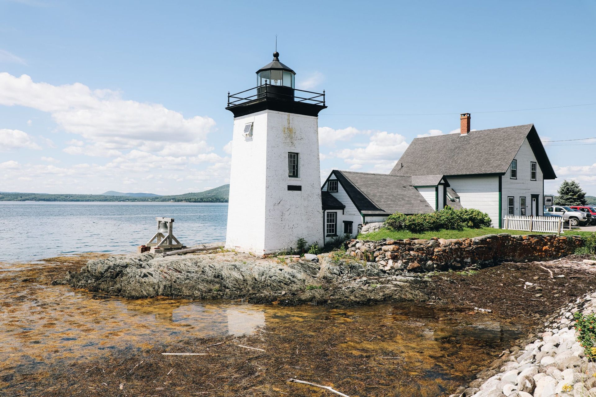 A lighthouse and a house on a small island in the middle of the ocean.