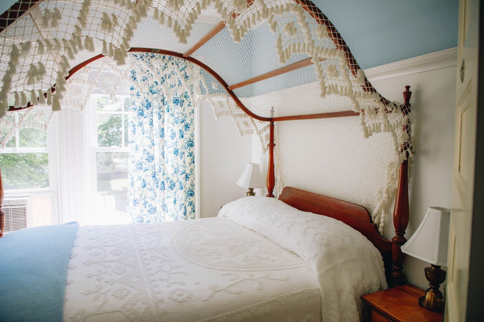 A bedroom with a canopy bed and a window.