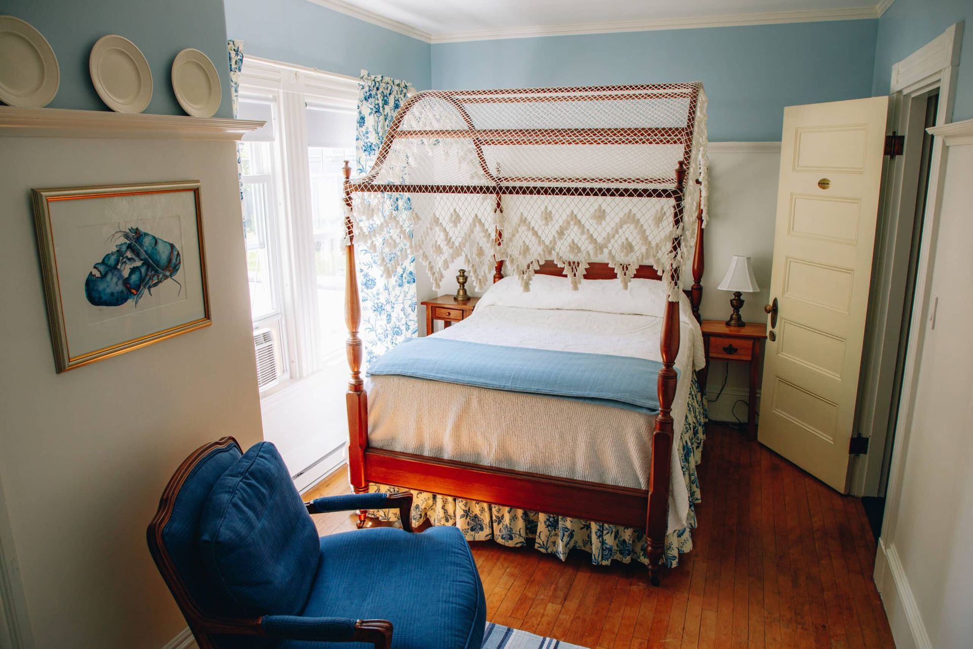 A bedroom with a canopy bed and a blue chair.