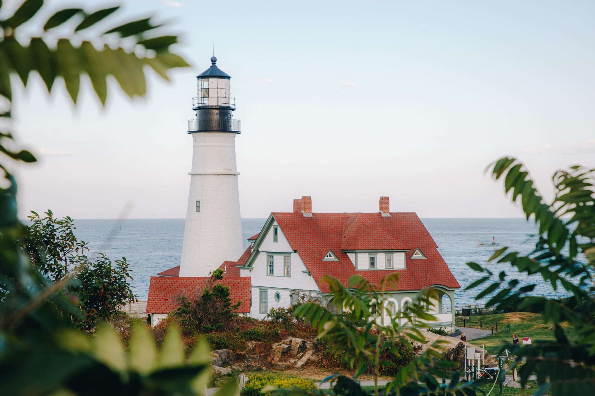 A lighthouse is sitting on top of a hill overlooking the ocean.