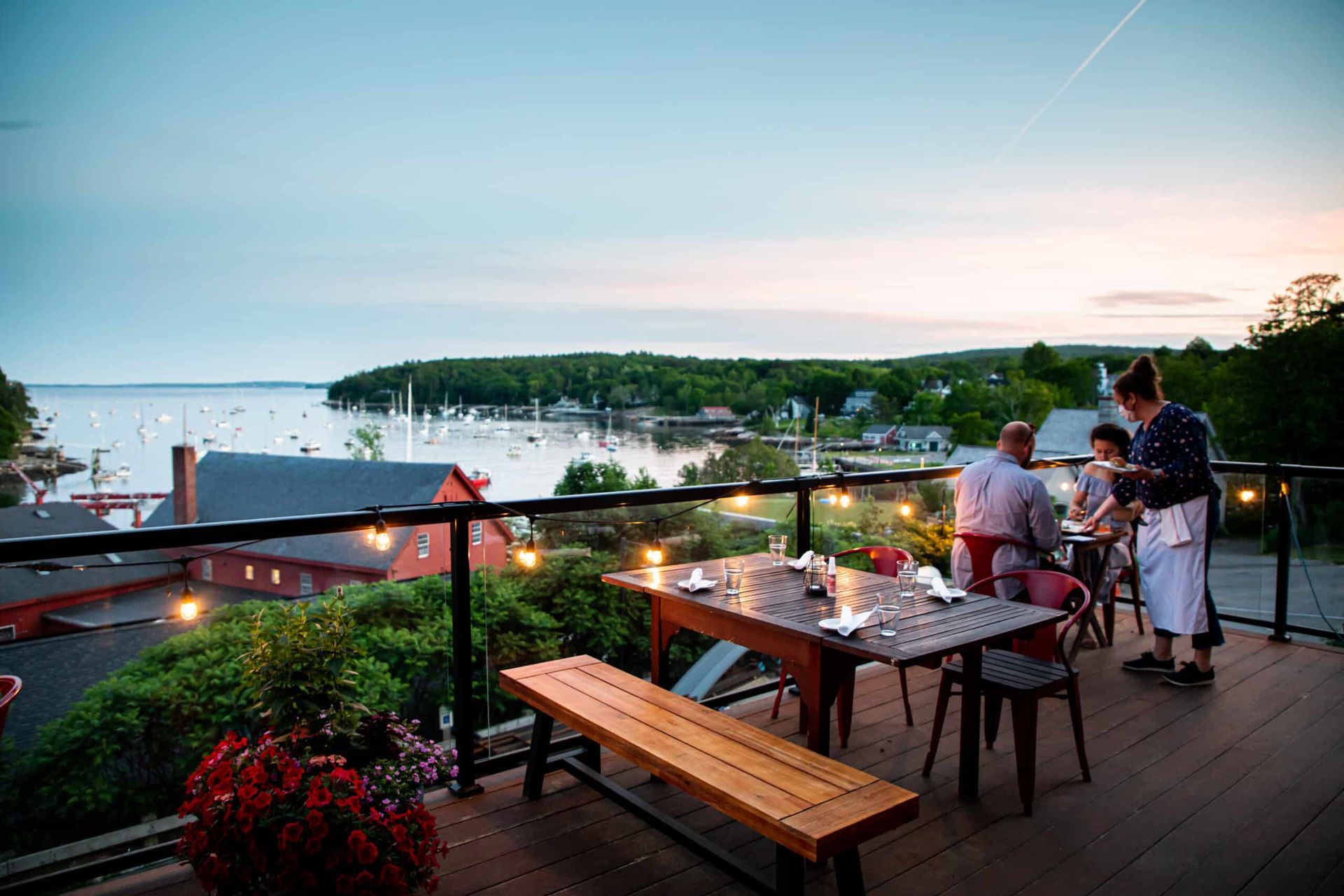 A group of people are sitting at a table on a balcony overlooking the ocean.