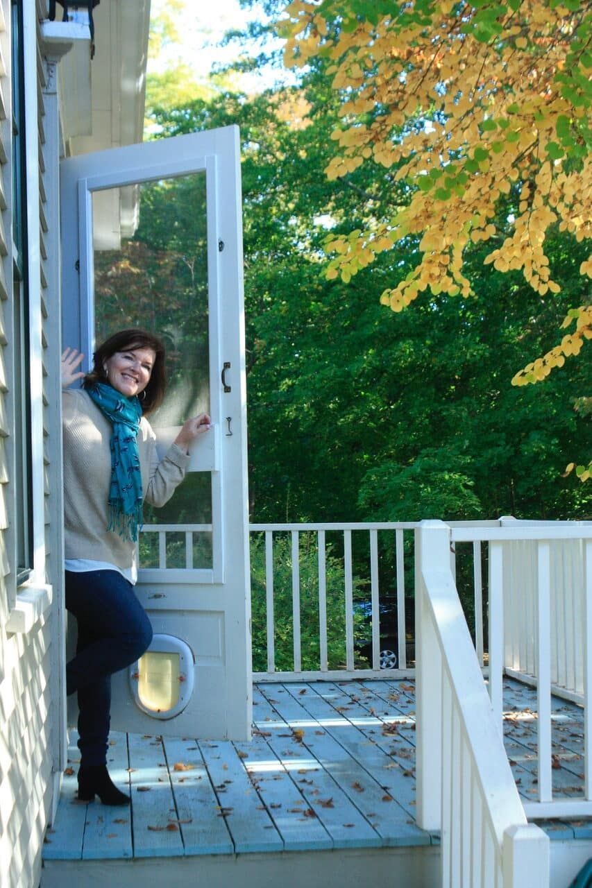 A woman is standing on a porch with her arms outstretched