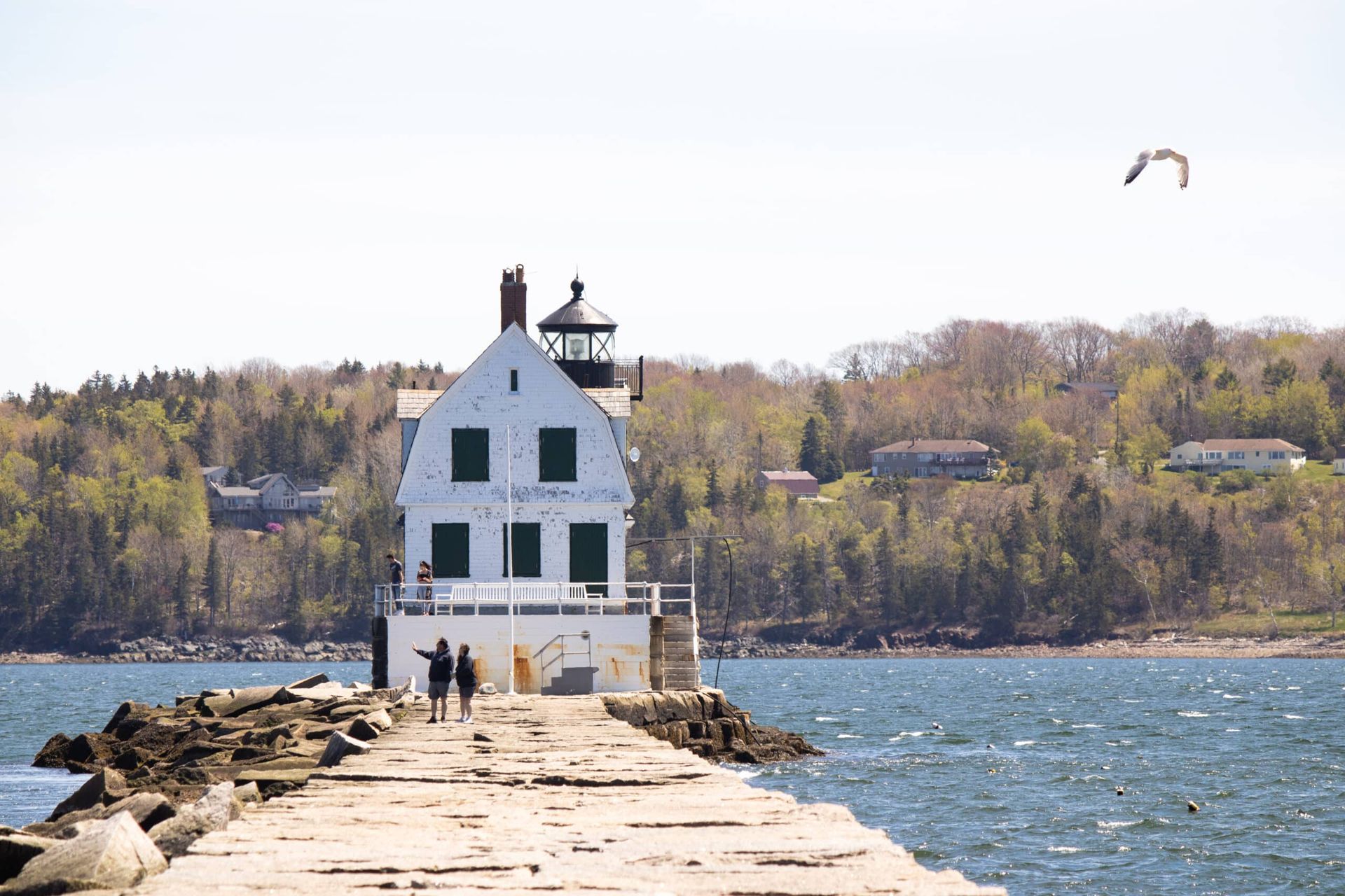 A couple walking on a pier with a lighthouse in the background