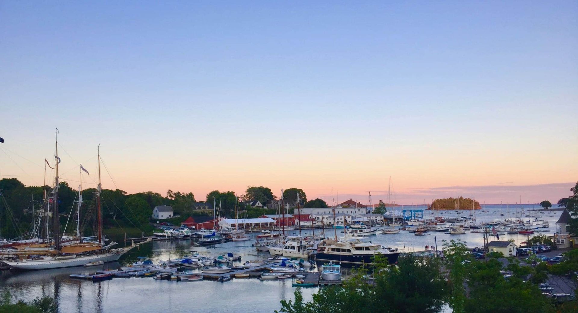 A harbor filled with boats and houses at sunset.