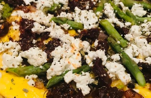 A close up of a pizza with asparagus , cheese and bacon.