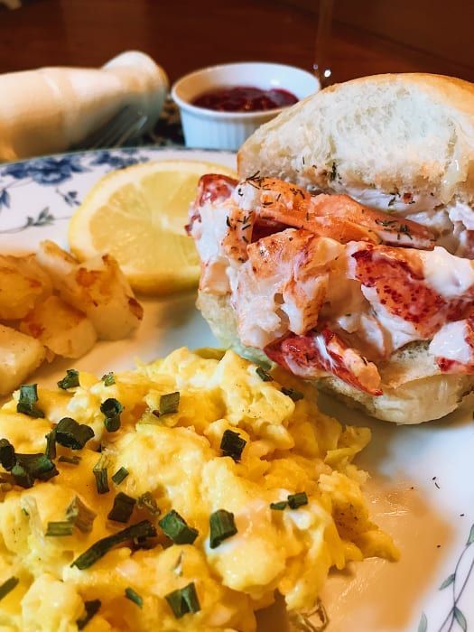 A plate of food with scrambled eggs and a lobster sandwich