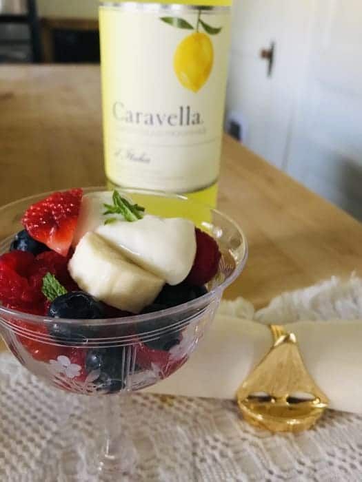 A bottle of caravella sits next to a bowl of fruit