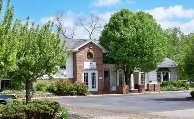 A black car is driving down the street in front of a large building.