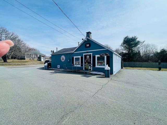 A person is pointing at a blue building with white trim