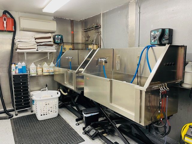 A room with two stainless steel sinks and a laundry basket.