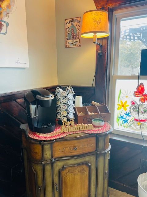 A coffee maker is sitting on top of a wooden cabinet in a room next to a window.