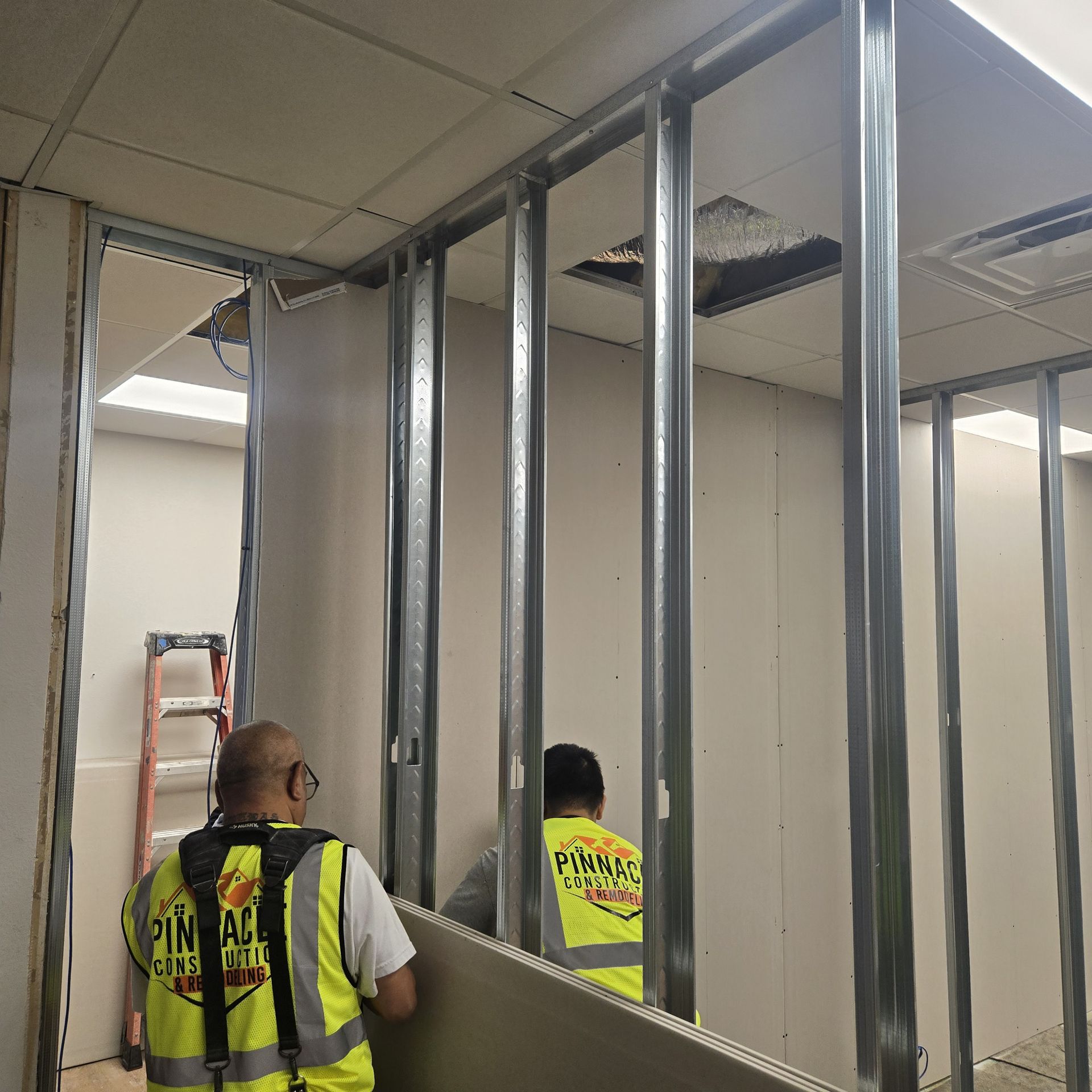 Construction workers in orange vests working on a concrete structure. Building site with wooden framework and tools.