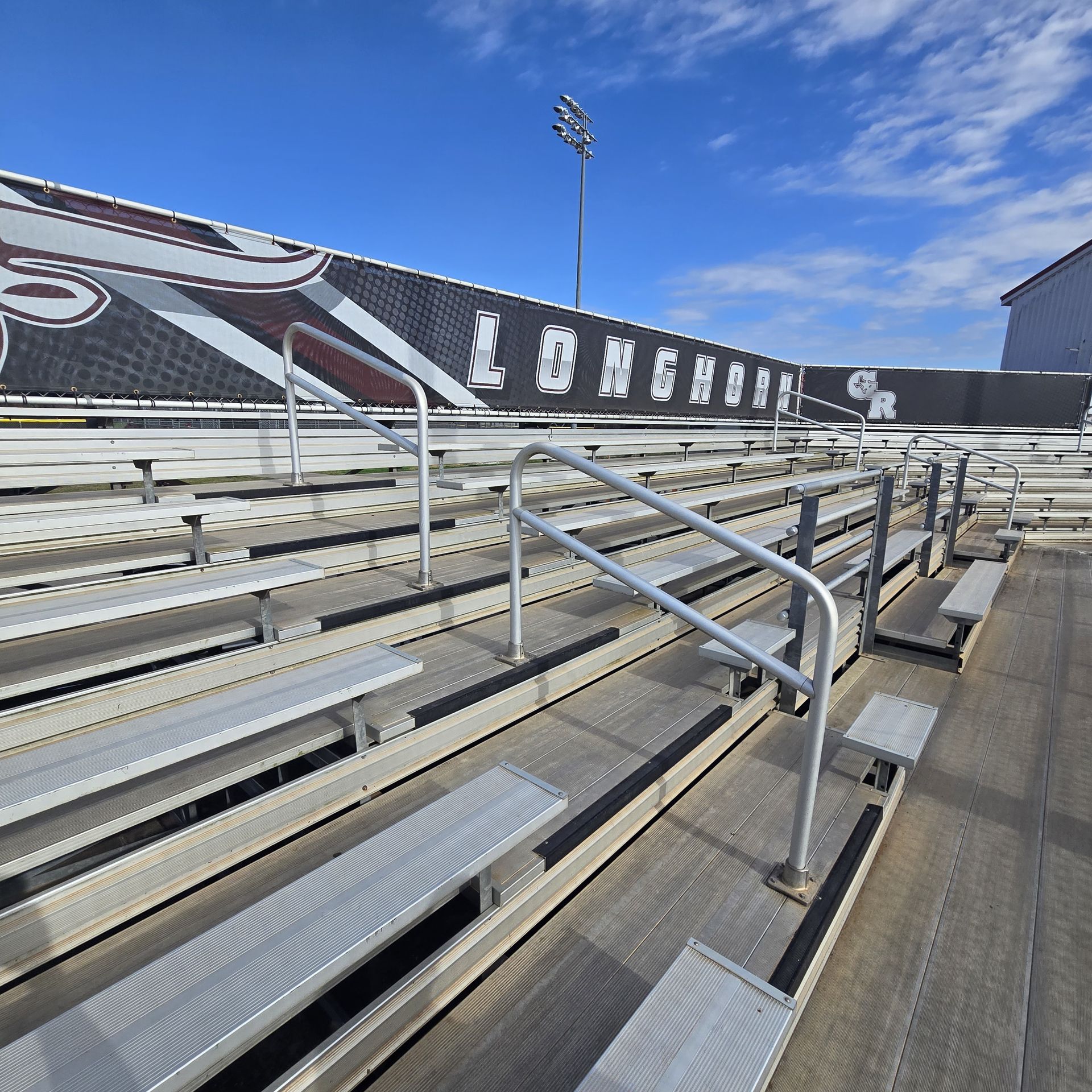 Construction worker in white hard hat and yellow vest surveys a construction site with cranes and buildings.