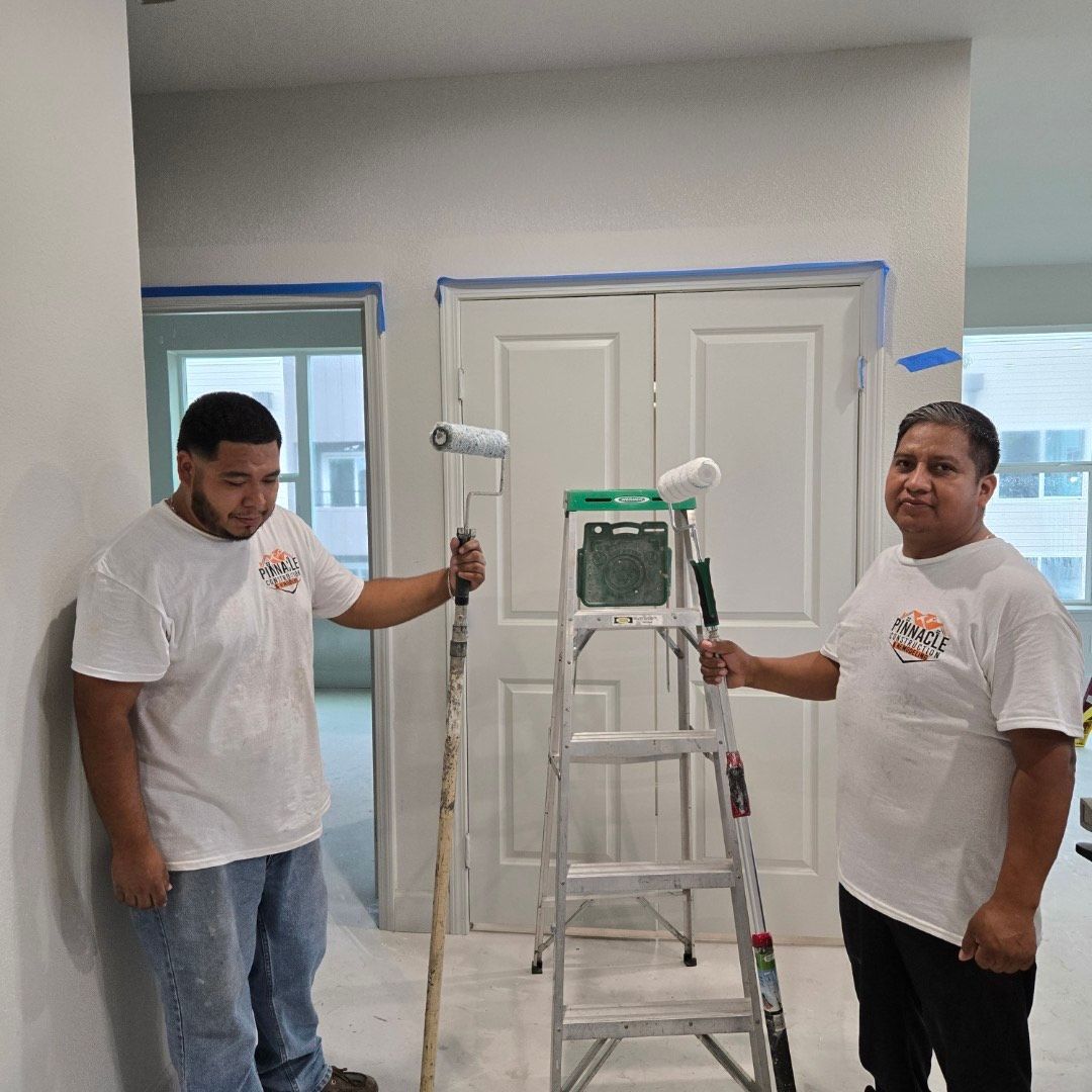 Four construction workers walk towards a building site. They wear hard hats and safety vests.
