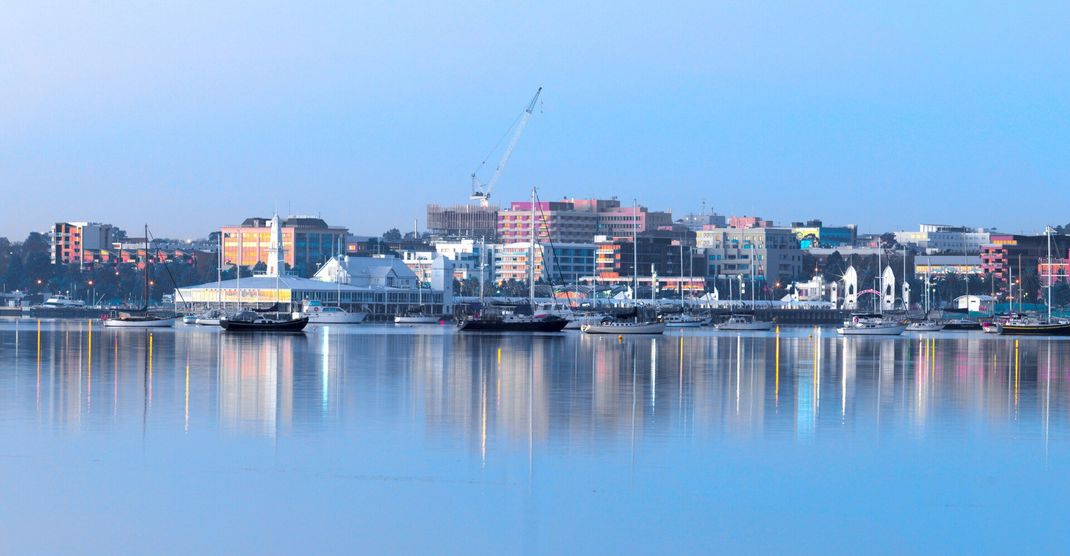 A city skyline over a body of water with boats in the water.