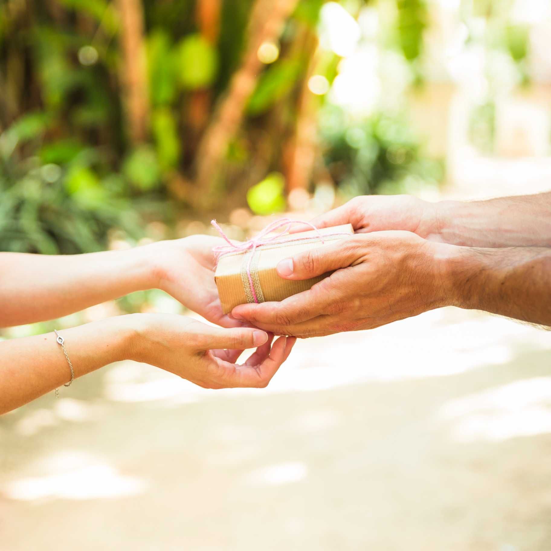 A man is handing a gift box to a woman.