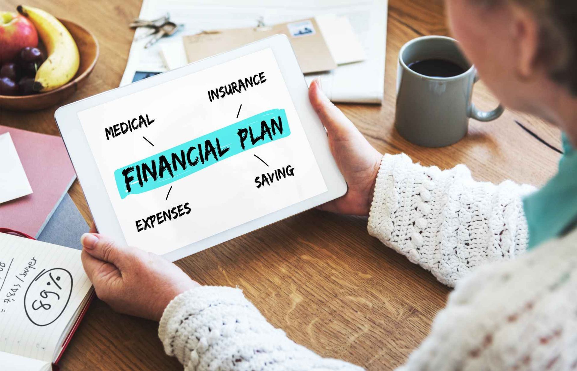 A woman is holding a tablet with the words `` financial plan '' written on it.