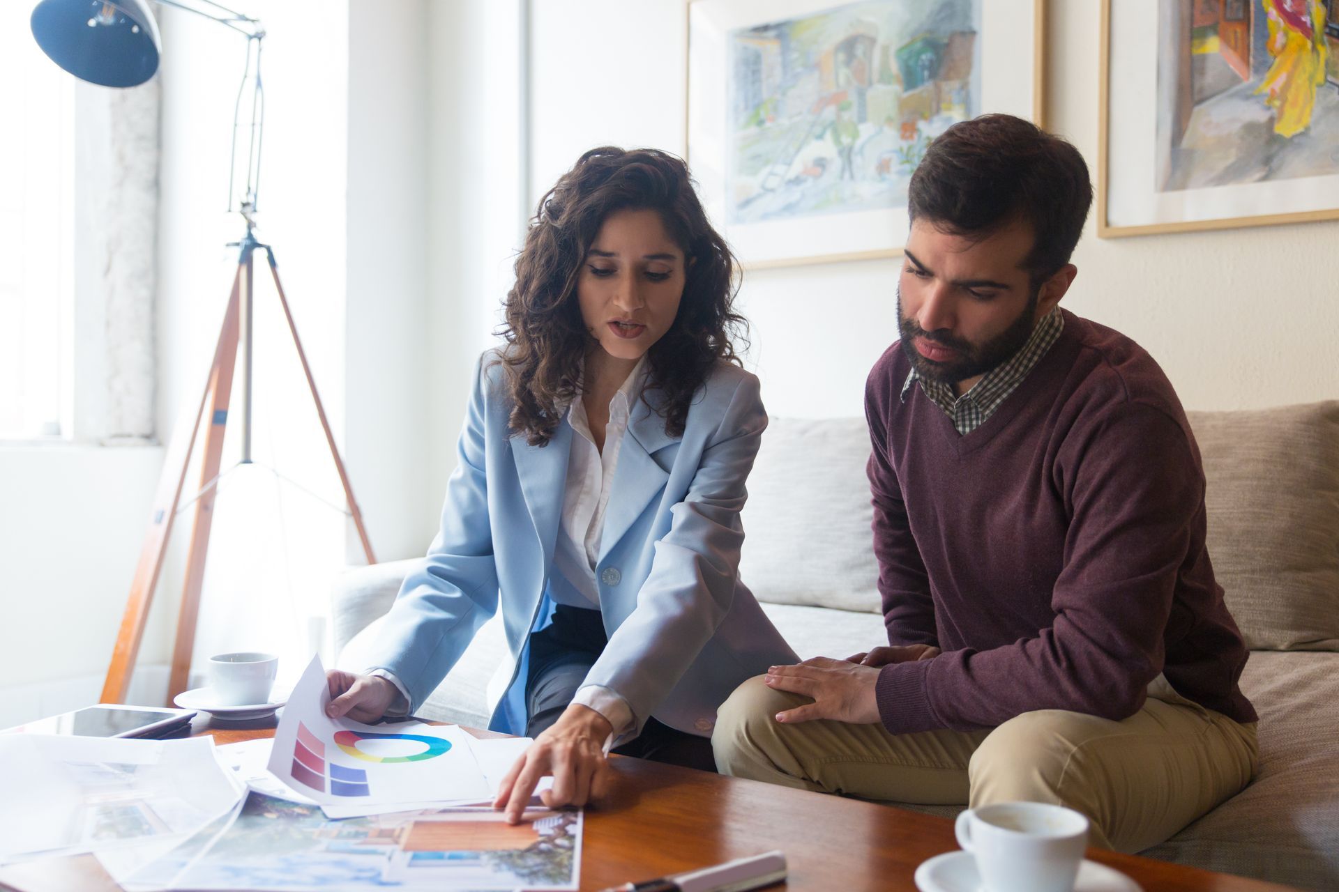 A man and a woman are sitting on a couch looking at a piece of paper.