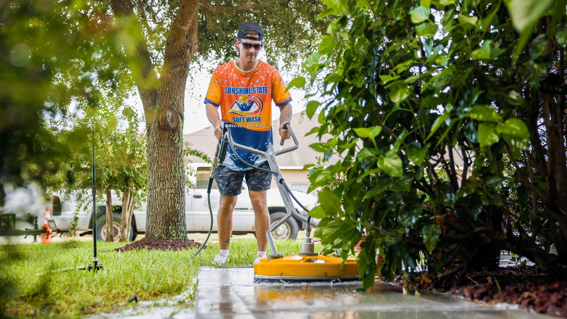 A man is using a pressure washer to clean a sidewalk.