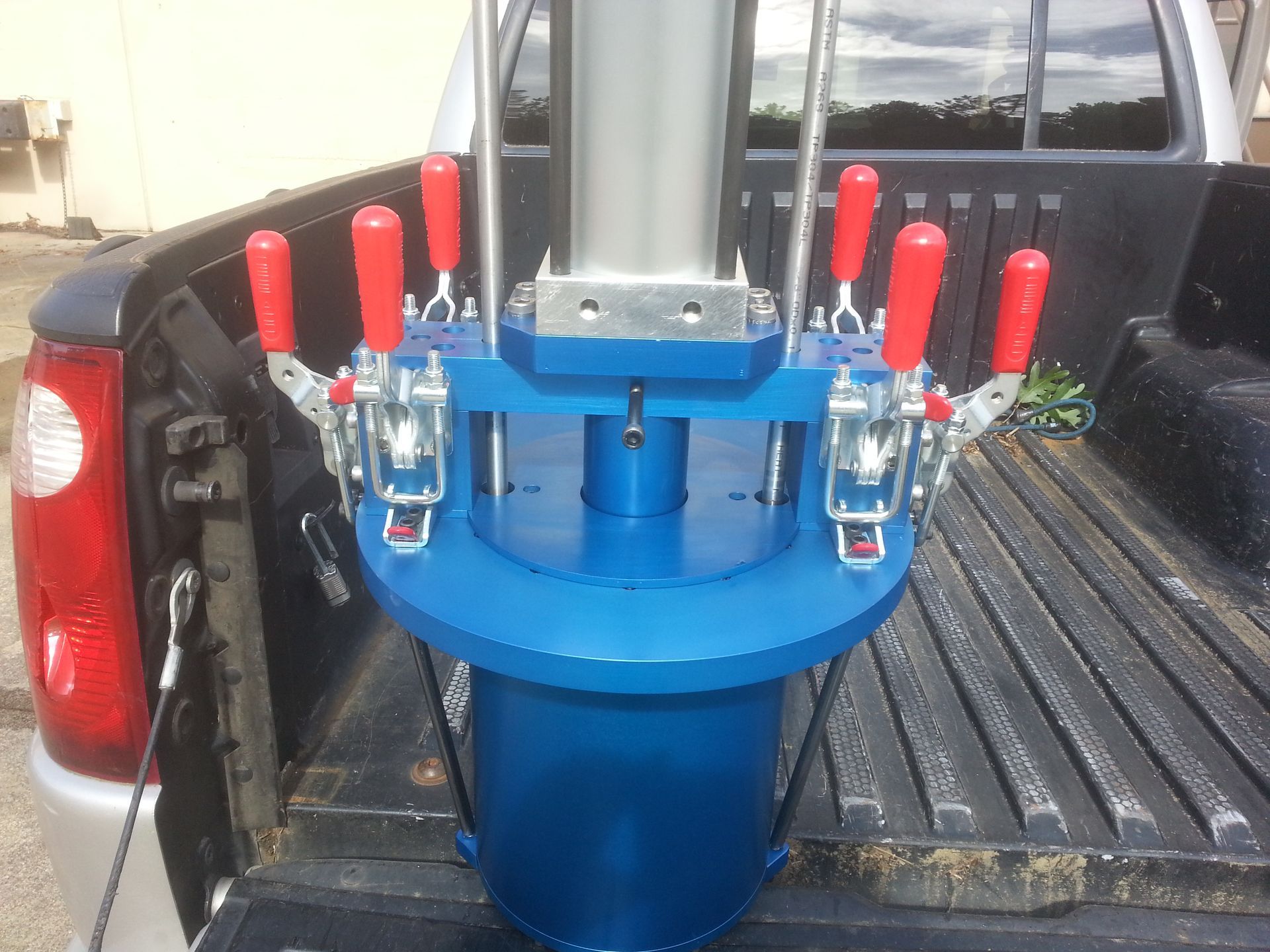 Blue and silver industrial tool with red handles, in a truck bed.