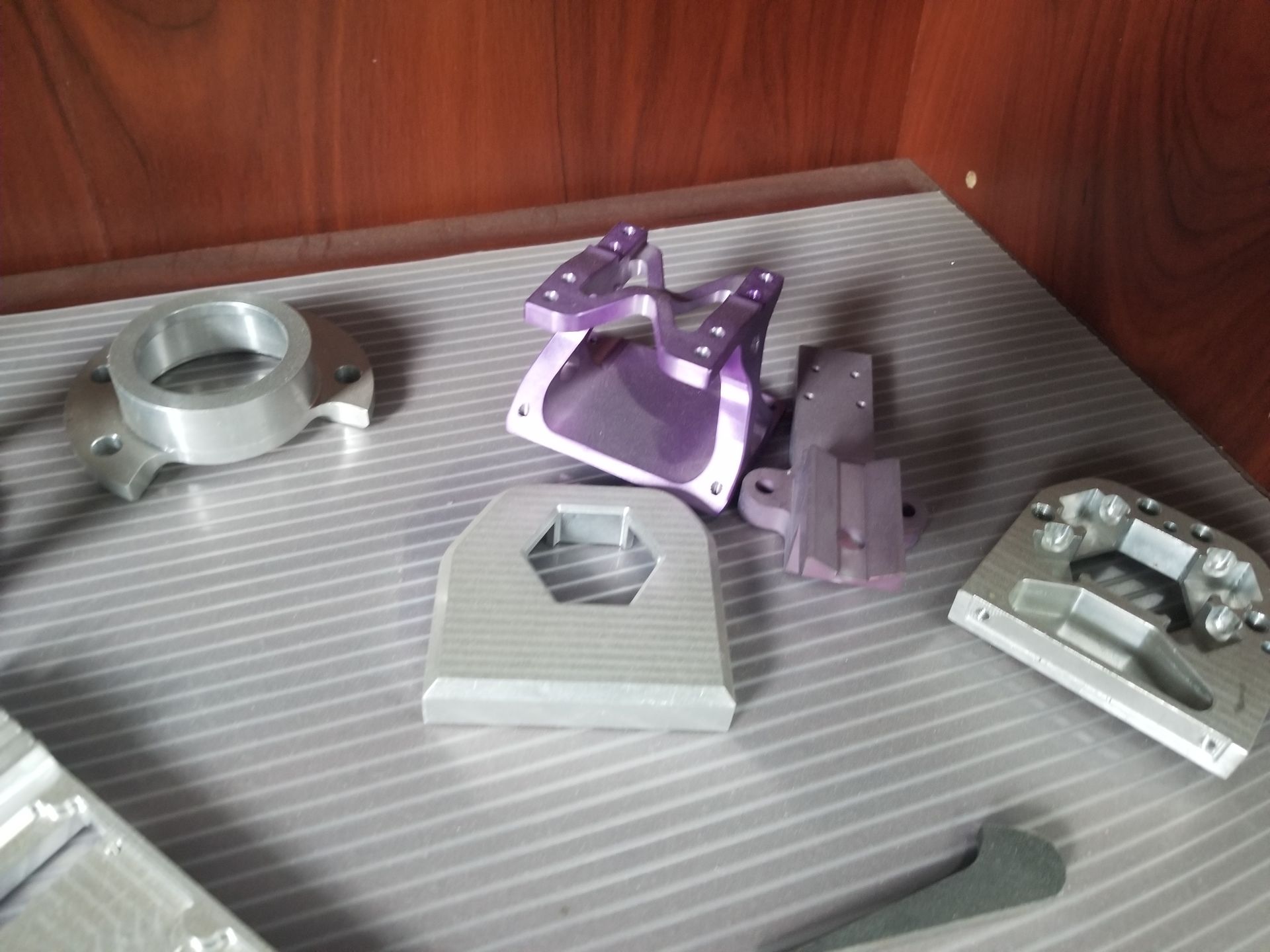 Metal machine parts in various shapes and colors are displayed on a shelf.