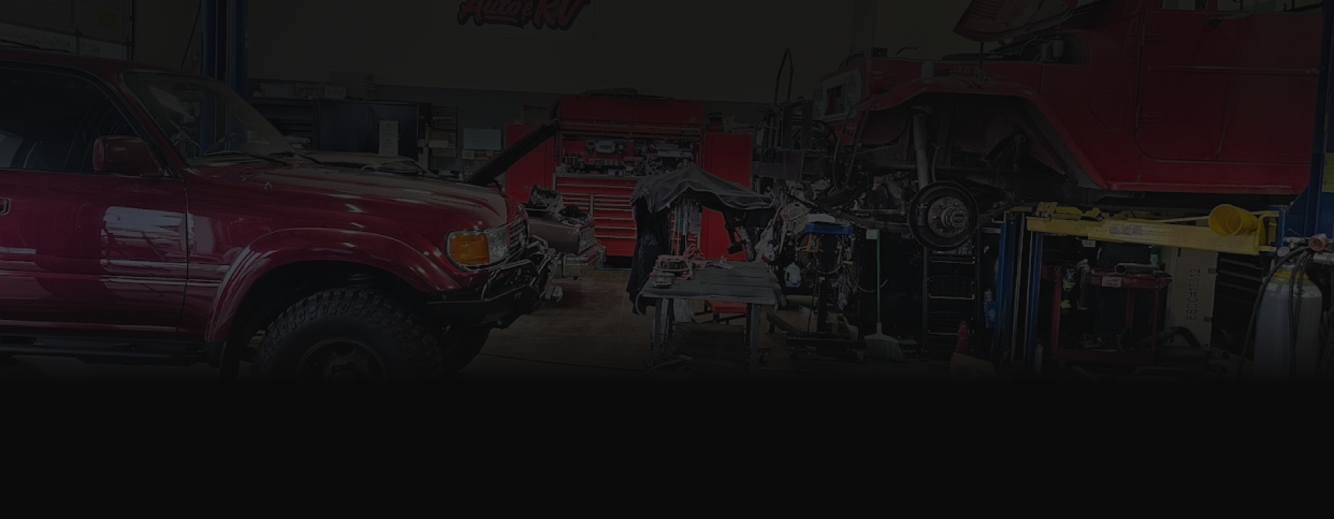 Red pickup truck and industrial equipment in a dim garage or workshop.