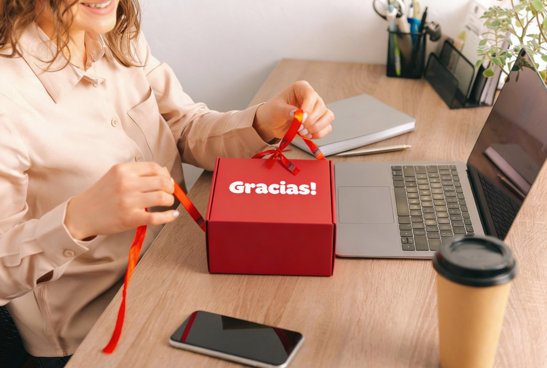 Uma pessoa está sentada em uma mesa desamarrando uma caixa de presente vermelha escrito 