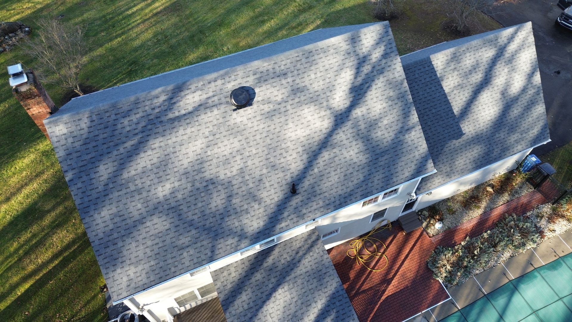An aerial view of a house with a roof and a pool.